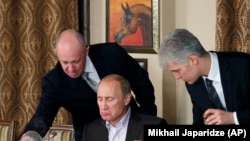 Российский бизнесмен, «повар Путина» Евгений Пригожин (слева) в своем ресторане подает пищу Владимиру Путину, 11 ноября 2011 года