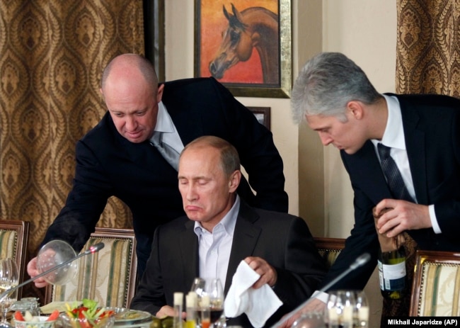 Prigozhin (left) and then-Russian Prime Minister Vladimir Putin (center) during a dinner with foreign scholars and journalists outside Moscow in November 2011.
