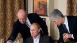 RUSSIA -- Yevgeny Prigozhin (L) assists Russian Prime Minister Vladimir Putin during a dinner with foreign scholars and journalists at the restaurant Cheval Blanc on the premises of an equestrian complex outside Moscow, November 11, 2011