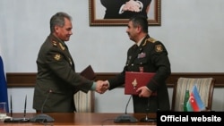 Azerbaijan - Defense Minister Zakir Hasanov (R) and his visiting Russian counterpart Sergey Shoygu sign an agreement after talks in Baku, 13 Oct2014