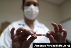 Sao Paulo-i ápoló mutatja a Sinovac gyógyszerét 2020. július 30-án.