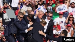 Republican presidential candidate and former U.S. President Donald Trump is assisted by U.S. Secret Service personnel after shots were fired during a campaign rally in Butler, Pennsylvania, on July 13.