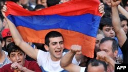 A demonstrator holds an Armenian flag as others shout slogans during a protest against an increase on electricity prices in Yerevan on June 25.