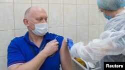 Russian cosmonaut Oleg Artemyev gets injected with the Sputnik V vaccine on December 18.