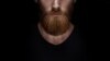 Perfect beard. Close-up of young bearded man standing against black background