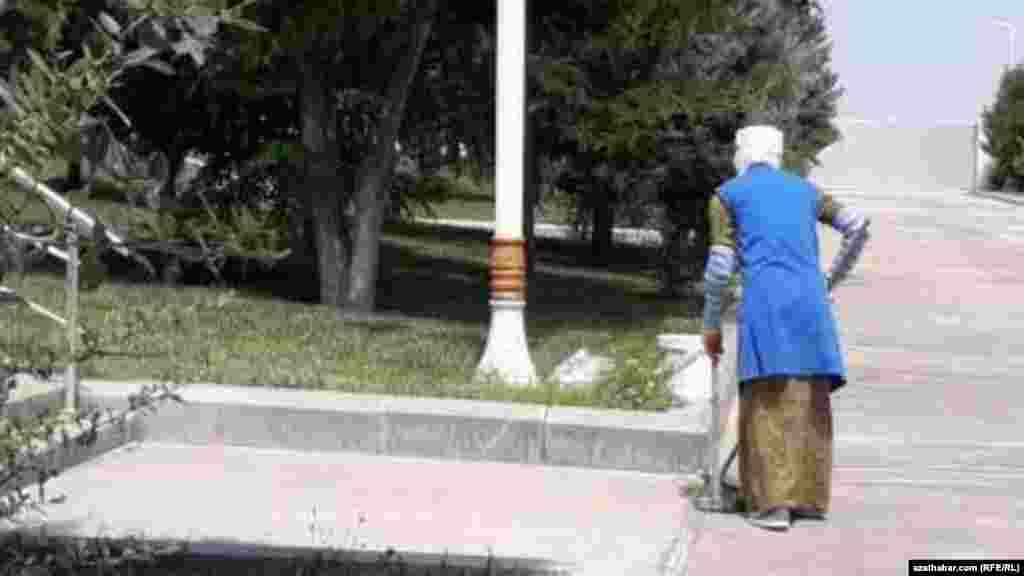 Kommunal hojalyk gullugynyň işgäri köçeleri süpürýär.