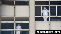 Medici care se uită pe ferestrele Spitalului Universitar din Coruna