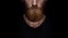 Perfect beard. Close-up of young bearded man standing against black background