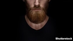 Perfect beard. Close-up of young bearded man standing against black background