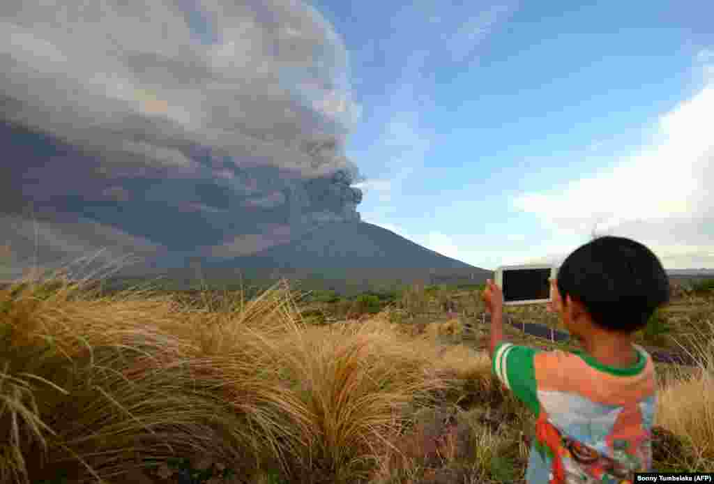 A boy takes pictures during an eruption of Mt. Agung on Indonesia&#39;s resort island of Bali. The eruption stranded tens of thousands of tourists after the ash cloud prevented planes from taking off. (AFP/Sonny Tumbelaka)