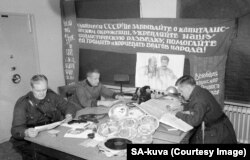 Финские офицеры с захваченными советскими пропагандистскими баннерами, картами, письмами и т.п.