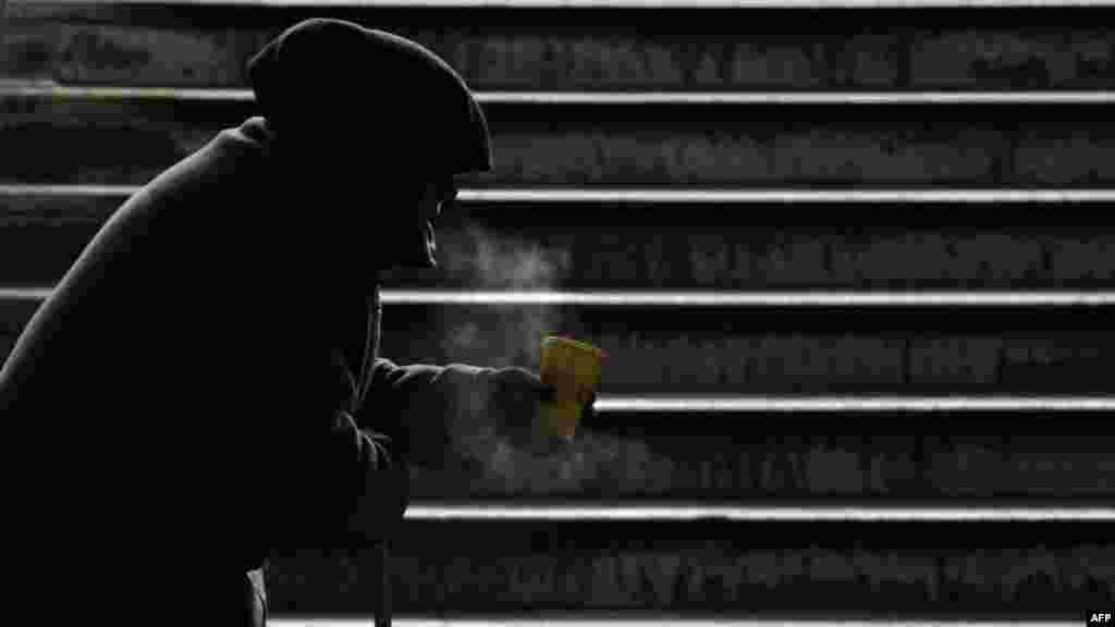 An elderly woman begs for alms at a subway entrance in Kyiv on February 8. (AFP/Sergei Supinsky) 