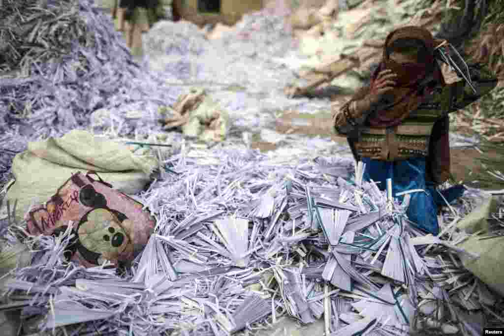 Razia, 9, fixes her scarf as she sorts papers before they are taken to a factory to be recycled in Lahore, Pakistan. (Reuters/Zohra Bensemra)