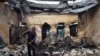 A man removes burned debris from a building following ethnic clashes in the southern Kazakh village of Masanchi in February. 