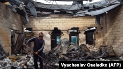 A man removes burned debris from a building following ethnic clashes in the southern Kazakh village of Masanchi in February. 