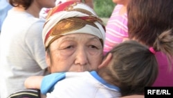 Бала құшақтаған қазақ әйелі Шаңырақтағы тағы бір толқу орнында. Алматы, 23 шілде 2009 жыл. 