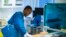 A Karolinska Kórház laboratóriumának orvosi személyzete a PCR-vizsgálat során használt géppel 2020. december 7-én, a Stockholm melletti Solnában