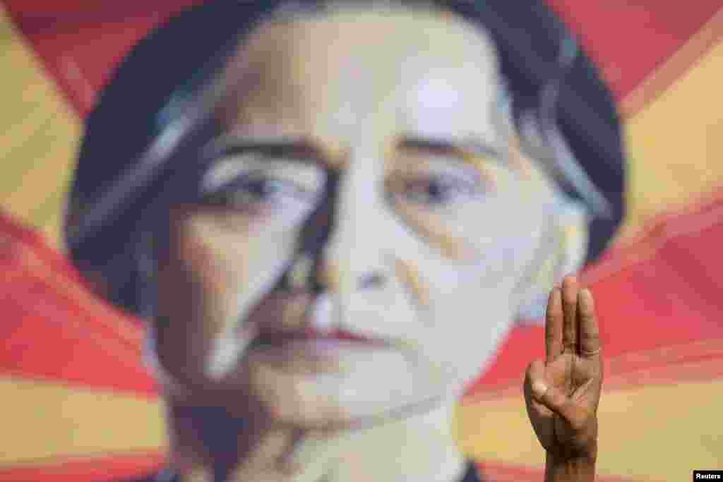 Едно лице го покажува поздравот со три прста пред плакат со ликот на Аунг Сан Су Ки за време на протестот против воениот удар во Јангон, Мјанмар, 15 февруари 2021 година.