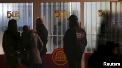 Forensic personnel are seen in front of a betting shop, the scene of a shooting that killed two soldiers and wounded five people.