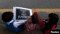 Пакистанские дети сидят на обочине дороги с плакатом - во время общественной акции протеста против изнасилования 5-летней девочки в городе Лахор. 17 сентября 2013 года