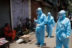 Қорғаныш киім киген медицина қызметкерлері тұрғындармен сөйлесіп тұр. Үндістан, 7 маусым 2020 жыл.