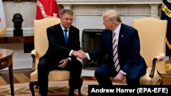 U.S. President Donald Trump (right) shakes hands with Romanian President Klaus Iohannis in the Oval Office of the White House in Washington, D.C., on August 20. 