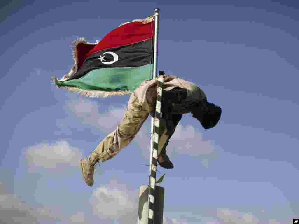 A former Libyan rebel fighter removes Muammar Qaddafi's slogans at the last checkpoint between Tarhouna and Bani Walid on September 8. (Photo by Alexandre Meneghini for AP)