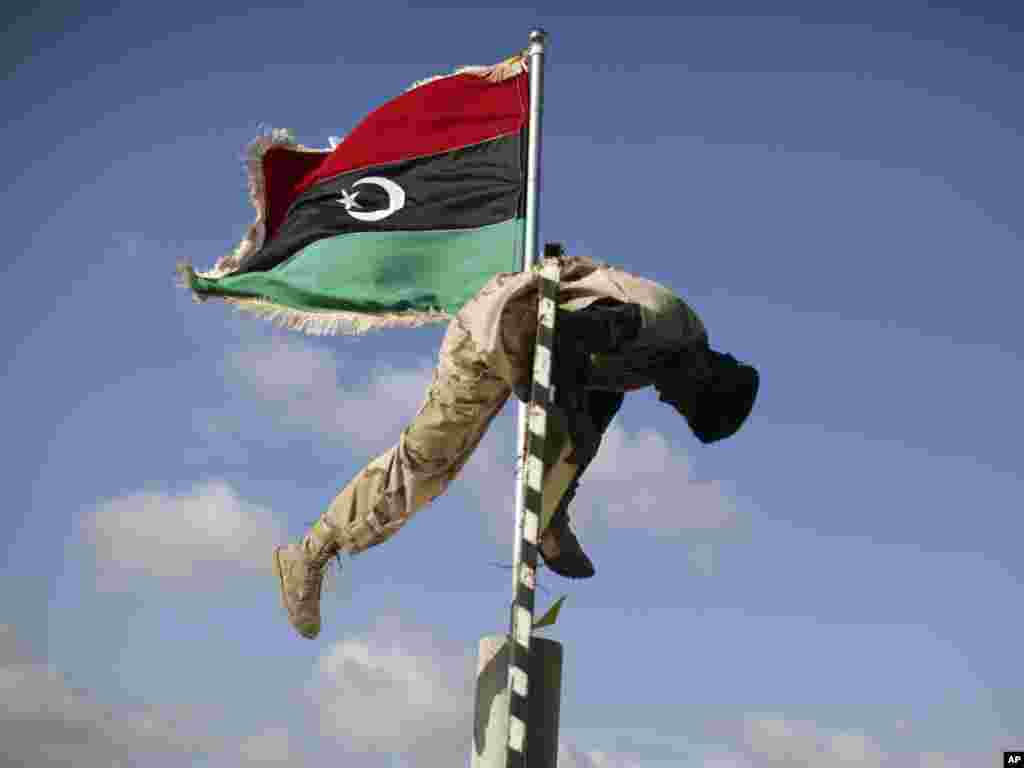 A former Libyan rebel fighter removes Muammar Qaddafi&#39;s slogans at the last checkpoint between Tarhouna and Bani Walid on September 8. (Photo by Alexandre Meneghini for AP)