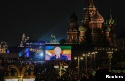 Vladimir Putin este văzut pe un ecran instalat în apropierea Catedralei Sfântul Vasile și a Pieței Roșii din Moscova, pe 30 septembrie 2022, înaintea unui concert care marchează așa-zisa anexare.