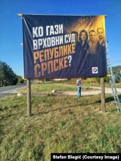 Jedan od mještana Podnovlja ispod ponovo postavljenog bilborda, 11. avgust 2026.g.