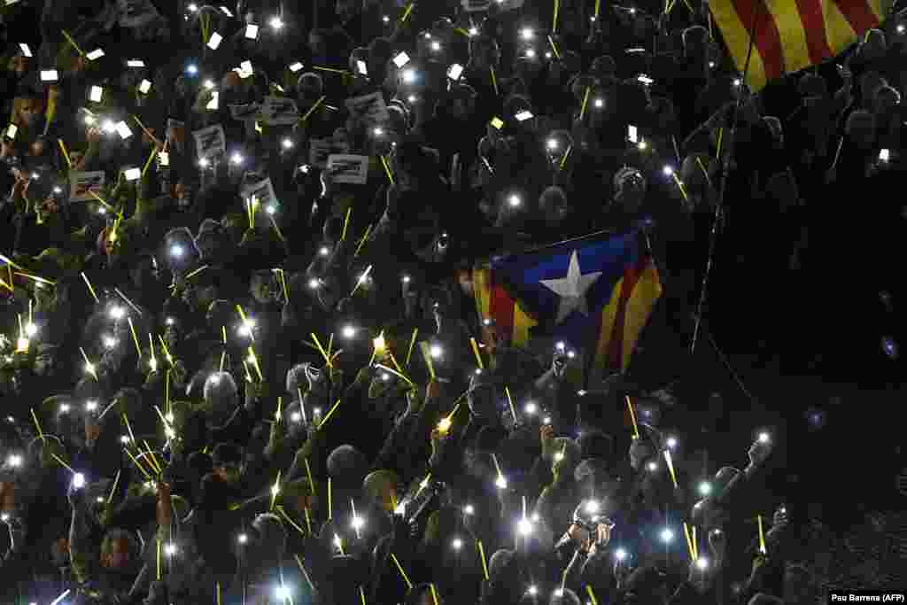 People hold their mobile phones to create the shape of a giant ribbon in front of the Generalitat palace -- the Catalan government headquarters -- at Sant Jaume Square in Barcelona during a demonstration calling for the release of jailed Catalan separatist leaders Jordi Sanchez and Jordi Cuixart. (AFP/Pau Barrena)