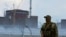 A soldier with a Russian flag on his uniform stands guard near the Zaporizhzhia nuclear power plant in Ukraine. (file photo)