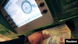 Russia -- A man holds ruble banknotes at an automated teller machine inside a branch of Sberbank in St. Petersburg, November 5, 2014