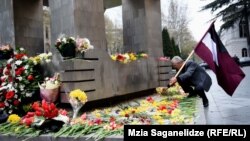 მოქალაქეები მემორიალთან სანთლებით და ყვავილებით მიდიან. 