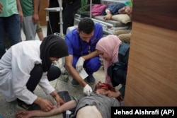 Infermierë duke trajtuar një burrë të plagosur gjatë një zënke familjare në një kamp për palestinezët e zhvendosur.