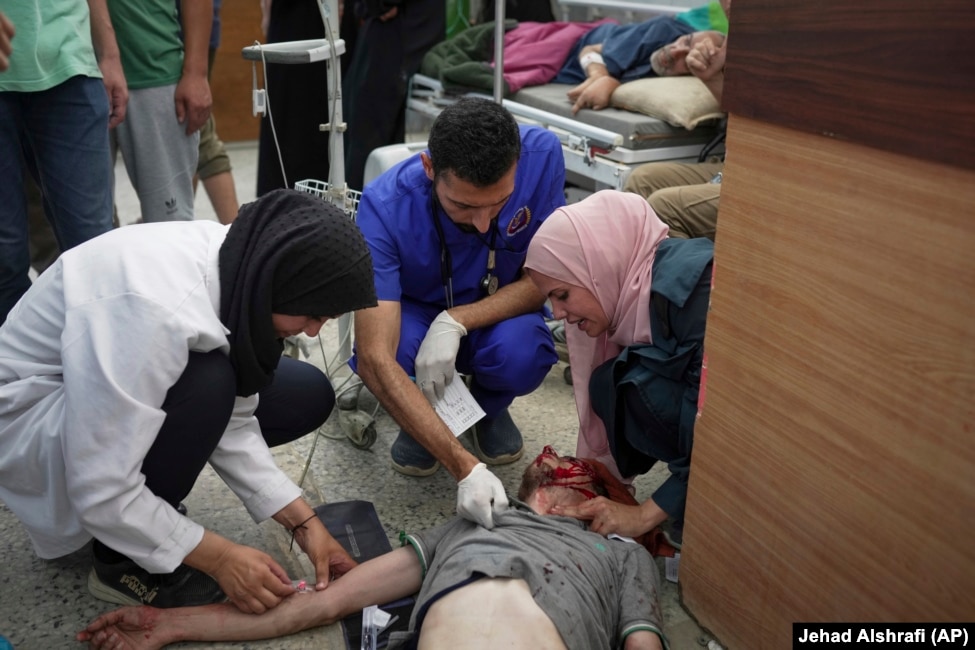 Infermierë duke trajtuar një burrë të plagosur gjatë një zënke familjare në një kamp për palestinezët e zhvendosur.