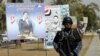 An Iraqi security officer patrols a street past provincial election posters.