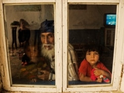A family peers out of a window in the Romany village near Bukhara.