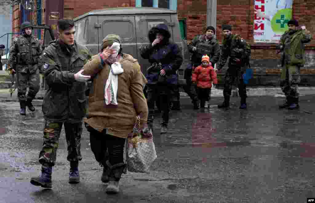 Ukrainian serviceman escort a wounded woman in the eastern Ukrainian city of Artemivsk, in the Donetsk region.