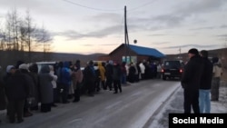 Residents of the remote Siberian town of Tura wait in line outside a food store. The "Z" symbol on the vehicle is a sign of support for Russia's war against Ukraine.