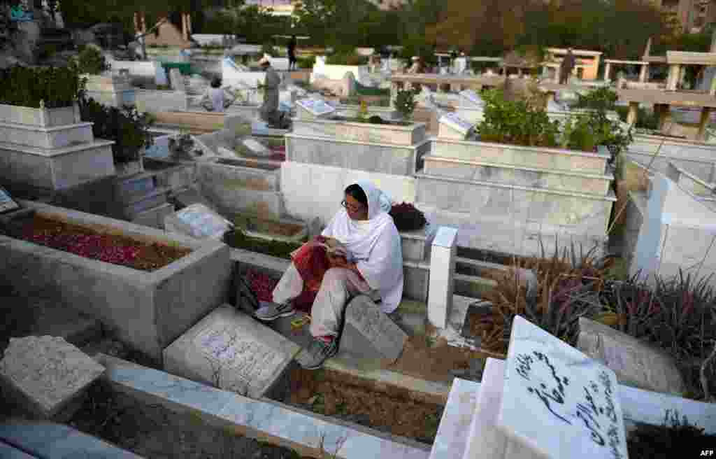 زنی پاکستانی و قرائت قرآن در کنار مزار درگذشتگان در کراچی