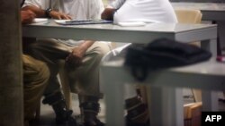 Гуантанамо әскери базасында қамауда отырған екі адамның сыртынан түсірілген сурет. 19 қаңтар 2012 ж.