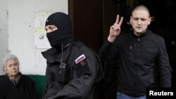 Russian opposition leader Sergei Udaltsov (right) gestures as he is escorted from his apartment after being detained in Moscow on October 17.