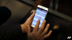 File photo:An Iranian shareholder monitors stock prices on his mobile phone at the Tehran Stock Exchange in Tehran, Iran, Tuesday, Feb. 2, 2016.(AP Photo/Vahid Salemi)