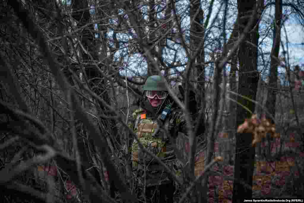 Український солдат повертається з передової позиції під прикриттям лісу.