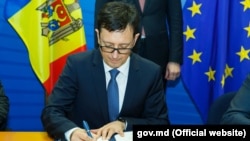 Octavian Armașu, semnând un acord de asistență cu UE la Bruxelles, noiembrie 2017