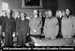 Під час підписання Мюнхенської угоди 1938 року. На передньому плані (зліва направо) глави урядів Великої Британії Невіль Чемберлен, Франції Едуард Деладьє, Німеччини Адольф Гітлер, Італії Беніто Муссоліні, а також міністр закордонних справ Італії Галеаццо Чіано