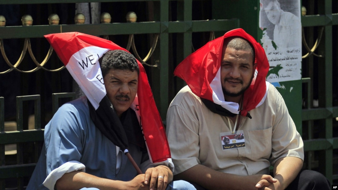 Egyptian protesters cover their heads from the sun with Egyptian flags, as they protest in Tahrir Square in Cairo on July 12, 2011