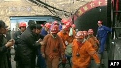 A TV screen grab shows rescuers carrying a miner away from the mine on a stretcher.