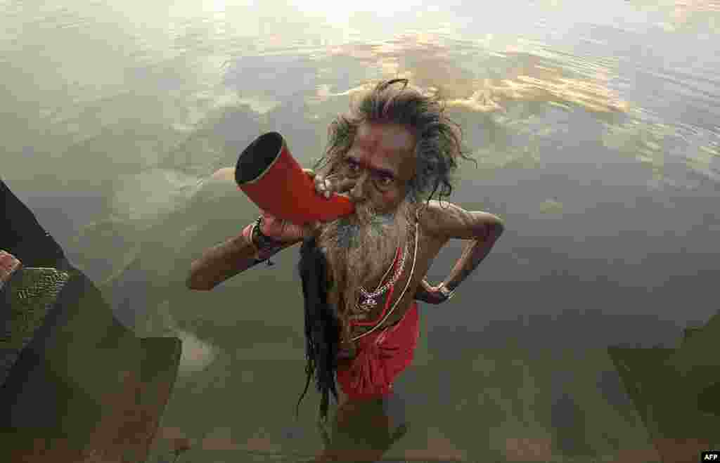 An Indian &quot;sadhu,&quot; or holy man, blows a buffalo horn on the eve of the traditional Kharchi Puja festival at Agartala, the capital of the northeastern Indian state of Tripura. (AFP/Arindam Dey)